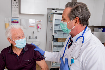 A White Male Medical Doctor Consults with an Elderly Senior Male Patient about Covid-19 Vaccine...