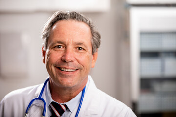 A Portrait of a White Male Medical Doctor with a Generic ID Badge wearing a Lab Coat and Stethoscope in a Hospital or Health Clinic. Mid Shot. - obrazy, fototapety, plakaty