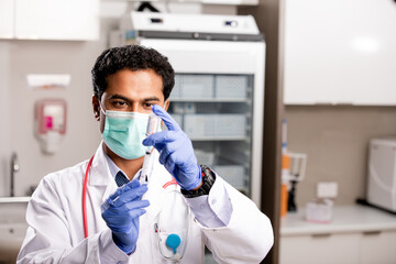 A Young Indian Male Medical Doctor Extracting a Covid-19 Vaccine Injection with a Syringe Needle...