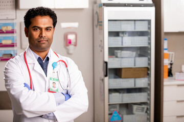 A Portrait of an Young Indian Male Medical Doctor with Generic ID Badge wearing a Lab Coat and...