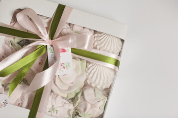 Homemade marshmallow in a gift box. Tied with a ribbon tied to a bow. On a white background. Close-up.