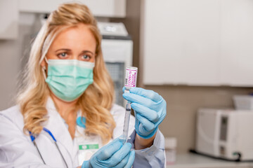 A Young Female Medical Doctor Extracting a Covid-19 Vaccine with a Syringe Needle Wearing Generic...