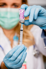 A Young Female Medical Doctor Extracting a Covid-19 Vaccine with a Syringe Needle Wearing Generic...