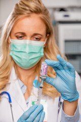 A Young Female Medical Doctor Extracting a Covid-19 Vaccine with a Syringe Needle Wearing Generic...