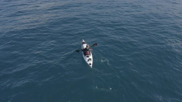 Single seat fishing canoe rowing at calm open sea water, Aerial view.