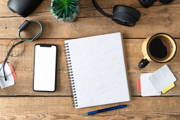 Blank notepad with pen, laptop, coffee, mobile phone with blank screen and headphones on wooden table top view. Office workplace background. Online work or education. Planning concept - Powered by Adobe