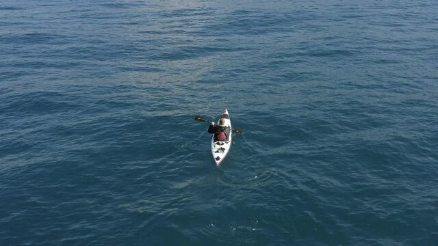Single seat fishing canoe rowing at calm open sea water, Aerial view.