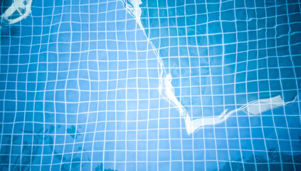 Abstract blue water in a swimming pool. There are reflections of leaves, branches of trees and hotels. late in the day. 