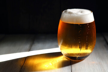 午後の強い光に照らされる丸みを帯びた背の低いグラスに注がれた泡立つビール