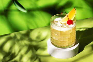 Whiskey sour trendy alcoholic cocktail with bourbon, lemon juice, egg white and ice, rocks glass on bright green background with hard light. Copy space