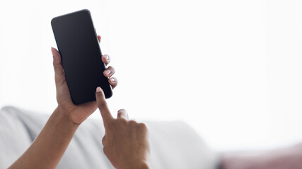 Young lady relax on sofa at home use phone, texting, chatting, shopping online, check mobile app