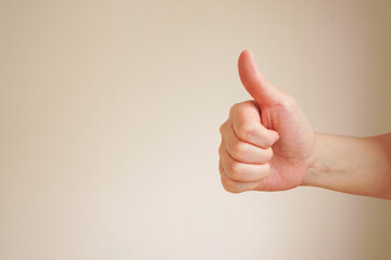 woman hand showing thumb up sign isolated on light background with copy space , hand gesture concept 