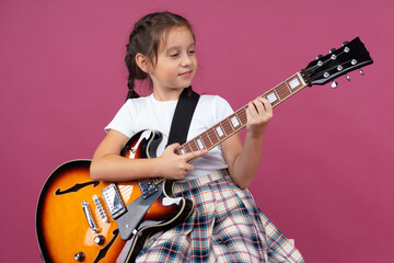A young girl in a school uniform plays an electric guitar