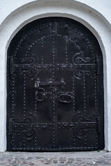 ancient black door in the old town with a wooden gate