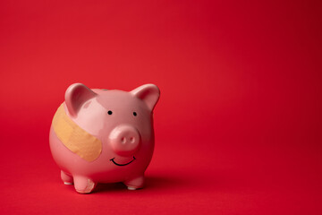 Broken piggy bank with beige adhesive on red background.