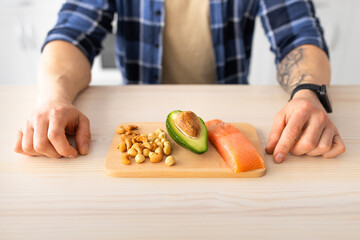 Healthy fat, protein diet and culinary concept. Mature man showing cutting board with salmon...