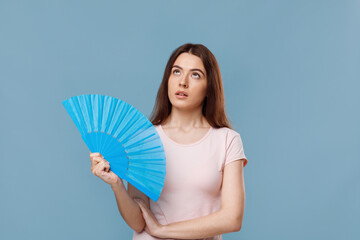 Pretty young lady with fan looking up, blue background