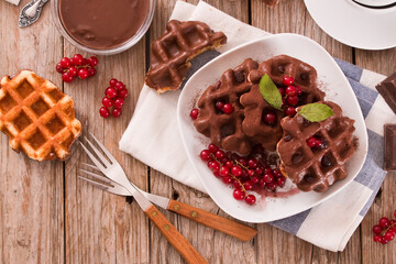 Waffles with chocolate topping, red currant and hazelnuts.
