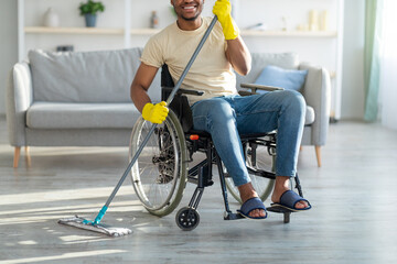 Cropped view of disabled black man in wheelchair cleaning his home, washing floor with mop
