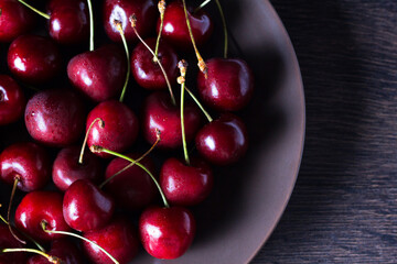 Cherries on a brown plate. Food with copyspace on a wooden table. Berries, snacks, healthy food. Vegan, vegetarian, diabetic, fruit.
