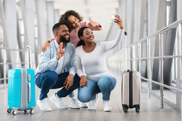 Black family of three traveling, taking selfie in airport