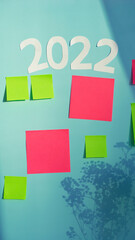 Multi-colored paper notes are glued on a blue board with sunlight from the window.
