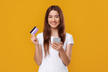 Naklejka premium Happy young lady with smartphone and credit card