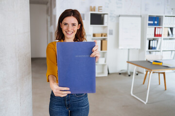 Happy young job seeker standing holding a CV