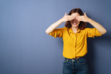 Playful young woman covering her eyes with her hands