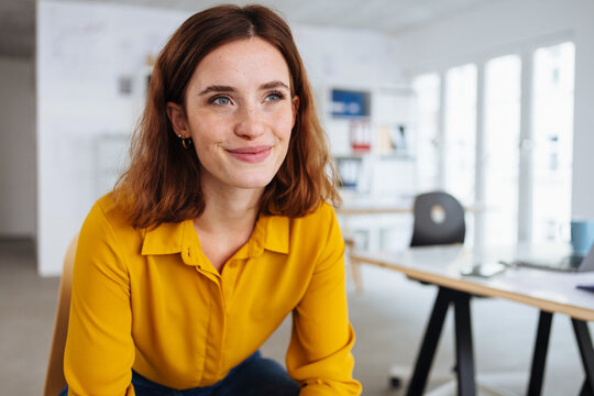 Young woman taking a break in the office sitting daydreaming