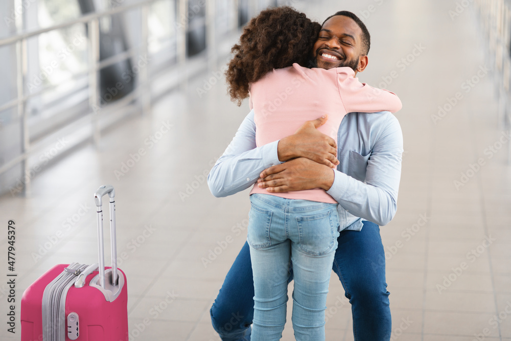 Wall mural Happy black man hugging his daughter in airport