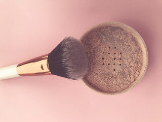 loose powder on a bright background. powder with white handle and gold nap holder. brush made of...