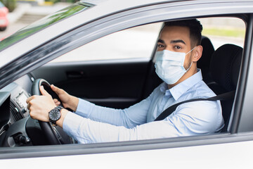 Young entrepreneur in face mask driving nice car