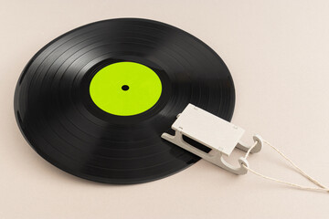 Minimal pop art holiday composition made with vinyl record with green label and sled against beige...