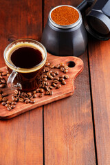 Coffee cup, geyser coffee maker and coffee beans on a wooden background. Ground coffee for making of coffee drinks. Copy space