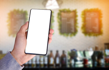 Smart mobile phone which has blank touchscreen holding in hand with blurred coffee shop background, concept for using smart mobile phone with online transactions.