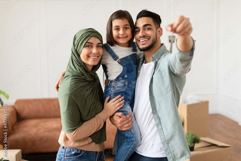 Wall mural happy muslim family showing keys of their apartment