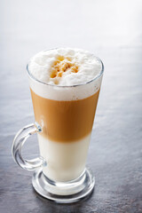 Latte macchiato coffee in transparent glass. Glass of latte macchiato on dark background