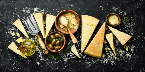Dairy products. Parmesan cheese, olives and snacks on a stone table. Top view. On a concrete background.
