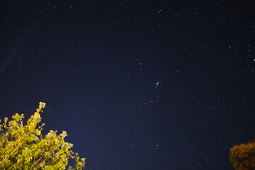 starry night with crisp sky and some clouds with a lot of constellations visible as well as some meteors or satellite trails shot from Tasmania.