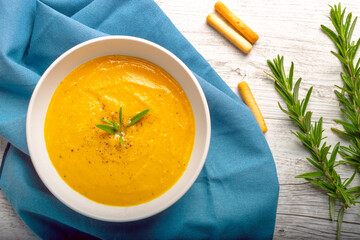 Pumpkin soup with linen napkin on light background.
