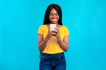 African American Woman Using Mobile Phone Posing Over Blue Background