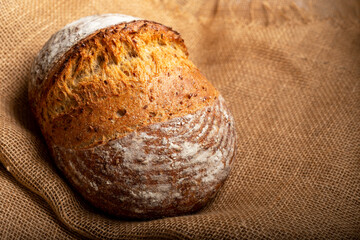 Wholemeal sourdough bread isolated on burlap cloth.