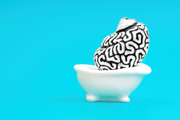 Huge human brain in a miniature bathtub on blue