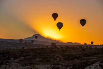 Hot air balloon with the sun rising from behind the mountain