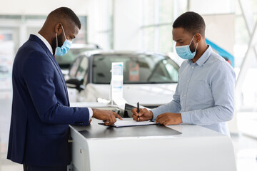 Black Man In Mask Buying Car In Dealership Office During Coronavirus Pandemic