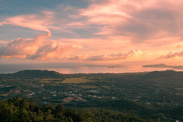 Panorama forest valley, mountains, village, sea and islands at sunset. Colorful clouds in the sky over tropical island. View from the top.