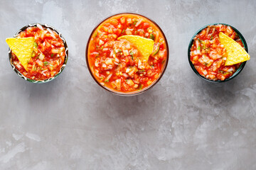 Salsa sauce and nacho chips on a gray background. Tortilla chips and salsa dip in bowl. Top view. Copy space