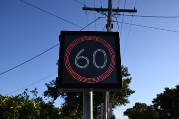 Alterable LED light speed limit sign showing 60, but also capable of showing 40, with blue sky in...