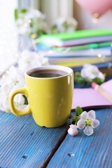 Cup of coffee, blank notebook, apple tree flowers and a stack of books, on a wooden windowsill, spring break concept, romantic mood